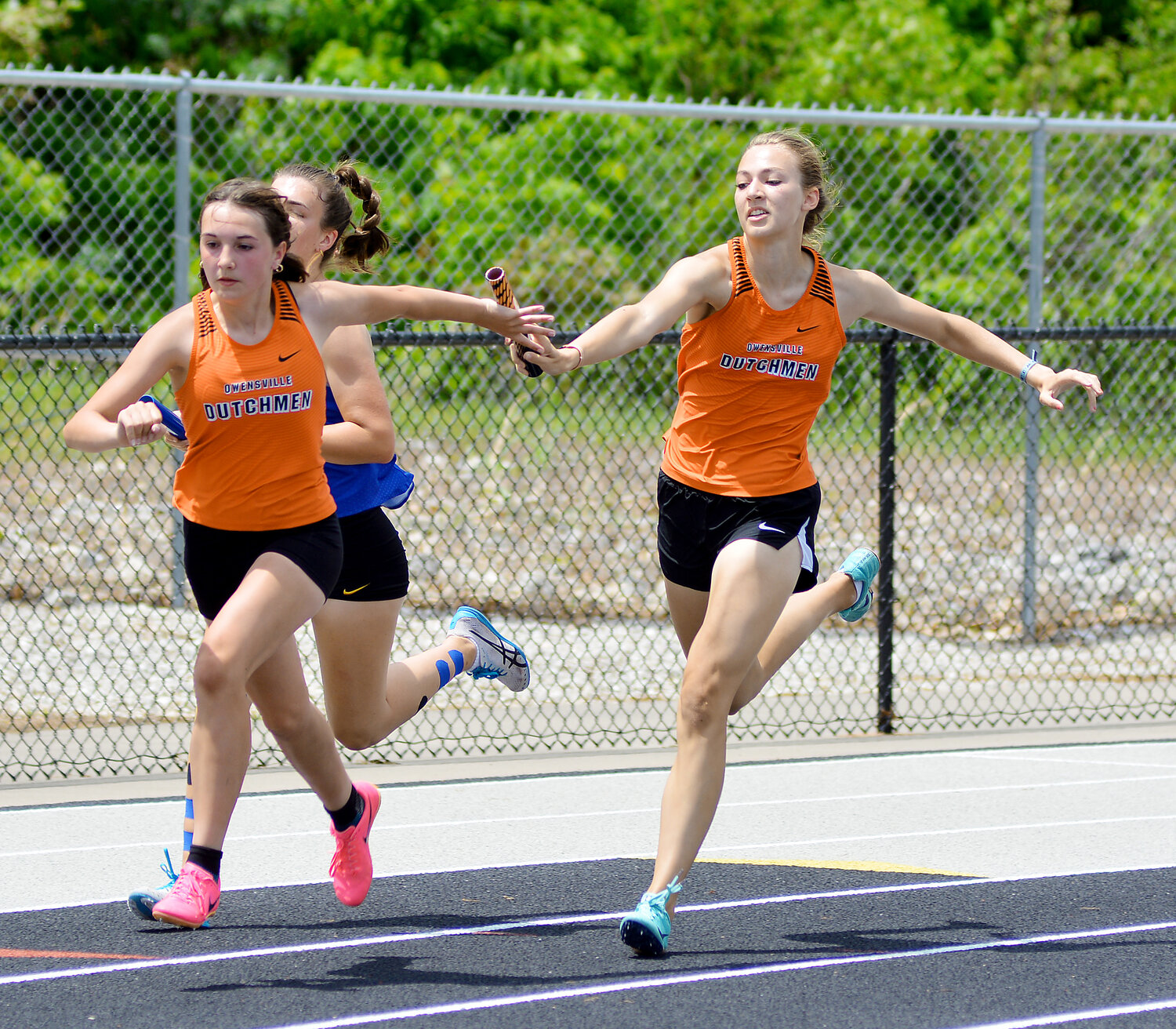 Emma-lee Wehmeyer (far left) reaches back for the baton from Dutchgirl teammate Ella Gehlert during the girls 4x200-meter relay Saturday at the Missouri State High School Activities Association (MSHSAA) Class 3, District 5 Track Meet at Waynesville High School.